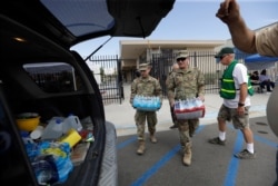 Members of the National Guard load water onto an SUV in the aftermath of an earthquake outside Trona High School in Trona, Calif., July 7, 2019.