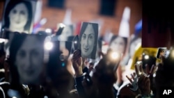 FILE - People hold pictures of journalist Daphne Caruana Galizia, who was slain in October 2017, as they protest in Valletta, Malta, Nov. 29, 2019.