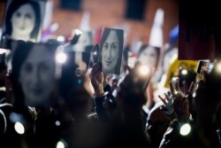 FILE - People hold pictures of journalist Daphne Caruana Galizia, who was slain in October 2017, as they protest in Valletta, Malta, Nov. 29, 2019.