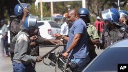 A cameraman is hit by the police during demonstrations in Harare on Aug. 3, 2016.