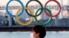 Un japonés usa una mascarilla protectora en plena pandemia frente a unos enormes anillos olímpicos en Tokio. [Foto de archivo]