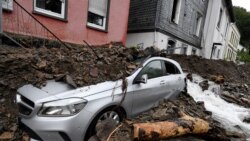 A car is covered in Hagen, Germany, Wednesday, July 15, 2021 with the debris brought by the flooding of the 'Nahma' river the night before. The heavy rainfalls had turned the small river into a raging torrent. (Roberto Pfeil/dpa via AP)