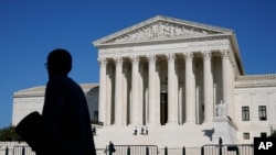 Officials stand on the Supreme Court steps on Capitol Hill in Washington, Tuesday, Sept. 22, 2020, as preparations take place for a private ceremony and public viewing in remembrance of Justice Ruth Bader Ginsburg.