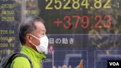 مردی از مقابل صفحه الکترونیکی نمایش ارزش سهام یک موسسه مالی در توکیو عبور می کند. آرشیو، ۱۱ نوامبر ۲۰۲۰