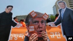 Un manifestante usa una máscara del presidente estadounidense, Donald Trump, (centro) junto a fotos del líder norcoreano Kim Jong Un y del presidente surcorerano, Moon Jae-in, (derecha) durante una manifesatción contra las politicas de EE.UU. contra Corea del Norte cerca de la embajada de EE.UU. en Seúl, el viernes, 25 de mayo, de 2018.