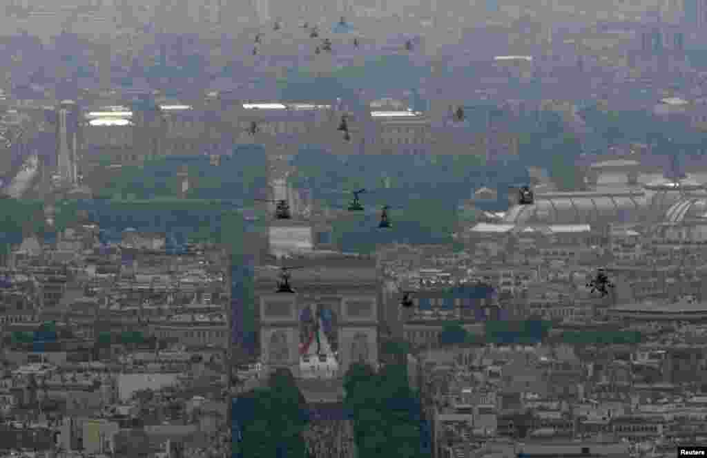 Helikopter-helikopter angkatan darat Perancis mendekati gerbang Arc de Triomphe selama parade Hari Bastille di Paris (14/7).&nbsp;(Reuters/Philippe Wojazer)