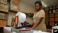 FILE - A worker cuts locally made biodegradable sanitary pads known as Makapads, made from waste paper with papyrus as the absorbent, that sell for half the price of imported pads, at the factory in Kampala, Uganda. 