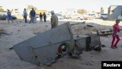 People stand next to the wreckage of a government MiG Libyan fighter jet that crashed during fighting Islamist fighters, in Benghazi, July 29, 2014.