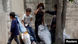 Syrian refugee children collect plastics as they stand along a street in south of Sidon, southern Lebanon, June 10, 2014.