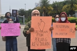 Para aktivis hak-hak perempuan membawa sejumlah poster dalam pawai untuk memperingati Hari Perempuan Internasional di Jakarta, 8 Maret 2021. (Foto: Adek Berry/AFP)