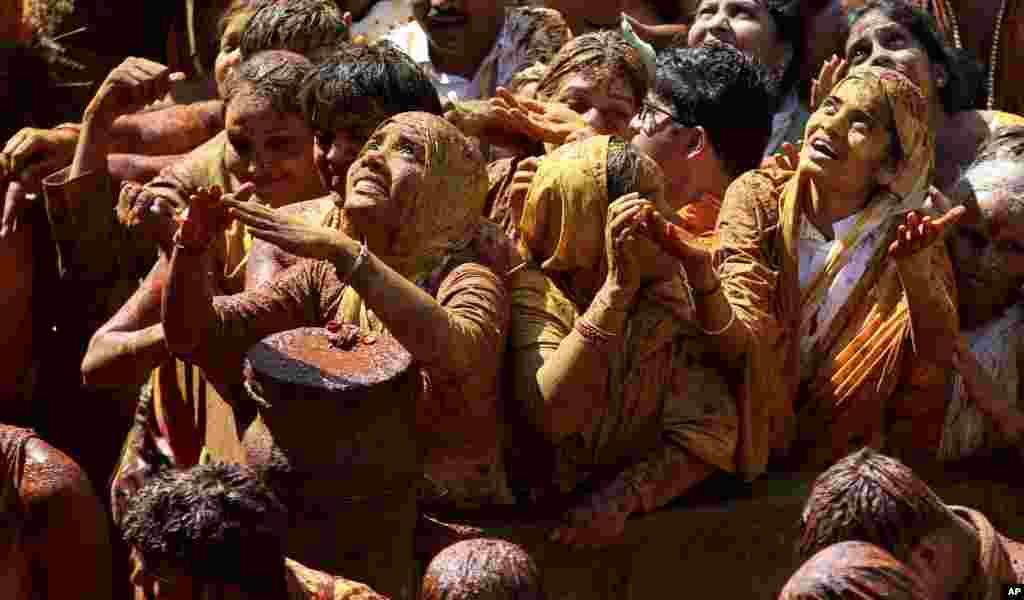 Devotees react during the anointment ceremony of the 58.8-foot monolithic statue of Jain god Gomateshwara at Shravanabelagola, 145 kilometers (91 miles) west of Bangalore, India. The 1,037-year-old statue is bathed with milk, turmeric, vermilion, saffron, sandalwood paste, powder of medicinal herbs and gold coins.