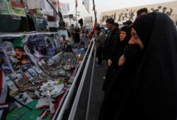 FILE - An Iraqi woman reacts as she looks at a makeshift memorial with personal belongings of those who were killed at anti-government protests at Tahrir Square in Baghdad, Iraq, Nov. 23, 2019.