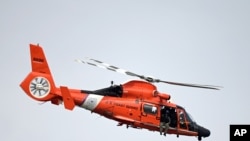 FILE - A U.S. Coast Guard helicopter patrols near in Jacksonville, Florida, Nov. 29, 2020. On Wednesday, a similar chopper picked up three Cubans stranded on an uninhabited Bahamiam island. 
