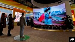 FILE - Visitors watch a man as he experiences a national anthem flag raising ceremony at an exhibition highlighting China's achievements at the Beijing Exhibition Hall, Oct. 23, 2017. On Nov. 4, 2017, China's rubber-stamp legislature made disrespecting the national anthem a criminal offense punishable by up to three years in prison.