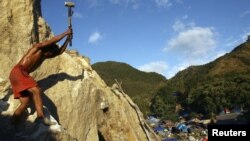 Seorang penambang memecahkan batu yang mengandung emas di Poboya, Sulawesi Tengah. (Reuters/Yusuf Ahmad)