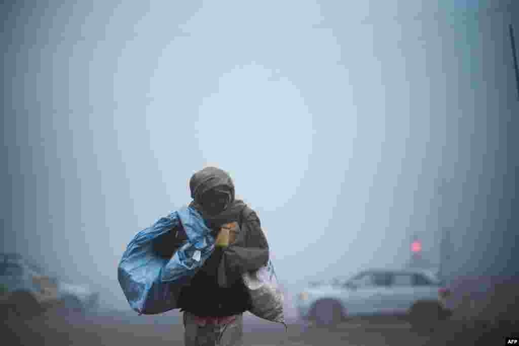 A man crosses a street under heavy foggy conditions in New Delhi, India.