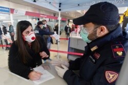A traveler wears a mask as she fills out a form at a check point set up by border police inside Rome's Termini train station, March 10, 2020.