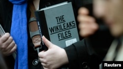A supporter of WikiLeaks founder julian Assange holds a copy of The WikiLeaks Files outside the Ecuadorian embassy in central London, Britain Feb. 5, 2016. 