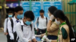 Students disinfect their hands to avoid the contact of coronavirus before their morning class at Santhormok high school, in Phnom Penh, Cambodia, Monday, Nov. 2, 2020. (AP Photo/Heng Sinith)