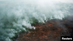 A forest fire is seen burning from a helicopter belonging to the Indonesian National Board of Disaster Management (BNPB) in Pelalawan, Riau province, Sumatra island, June 10, 2016 in this photo taken by Antara Foto. 