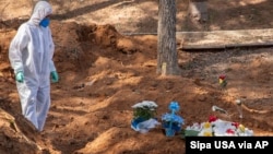 Une femme enterrant une victime de la maladie Covid-19 au cimetière Saint Louis à São Paulo, 23 juin 2020. (Sipa USA via AP)