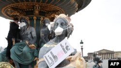 Seorang demonstran memakaikan masker pada patung-patung dalam unjuk rasa memprotes polusi udara di place de la Concorde di Paris, on 31 Maret 2018. / AFP PHOTO / JACQUES DEMARTHON