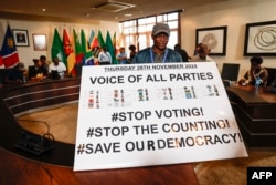 A member of a Namibian opposition political party displays a banner calling for a halt to voting inside the boardroom of the Electoral Commission of Namibia in Windhoek on Nov. 28, 2024.