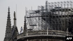 Trabajadores en el techo de la catedral de Notre-Dame de Paris, una semana después de un incendio que devastó la catedral.