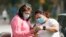 In this file photo, women wear masks as they check a mobile phone Wednesday, July 1, 2014, in Houston, Texas. (AP Photo/David J. Phillip)