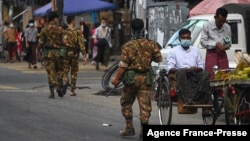 FILE - Soldiers walk along a street as they search for protesters, who took part in a demonstration against the military coup, in downtown Yangon, Myanmar, May 6, 2021.