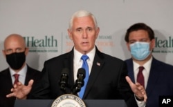 Vice President Mike Pence, center, gestures as he speaks during a news conference with FDA Commissioner Dr. Stephen Hahn, left, and Florida Governor Ron DeSantis, right, at the University of Miami Miller School of Medicine, July 27, 2020.