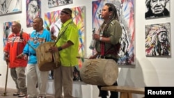 FILE - Native American climate activist and artist Jacob Johns, right, drums with members of the Santa Clara Pueblo tribe of New Mexico in Santa Fe, July 11, 2024. Johns was shot at a protest in the state in 2023.