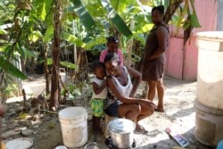 Frena Remorin, 30, (seated) cooks bananas in the improvised kitchen in the yard of her house in Jean-Rabel, Haiti, Jan. 31, 2020.