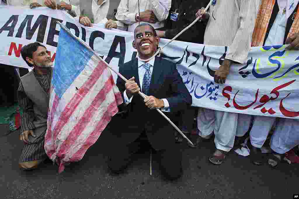A supporter of the Human Rights Network group wears a mask of U.S President Barack Obama with a noose around his neck while holding the U.S flag during an anti-American rally in Karachi, Pakistan on February 26, 2012. (Reuters)