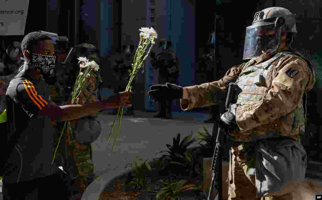 A demonstrator offers flowers to a National Guardsman outside the office of Los Angeles County District Attorney Jackie Lacey during a protest June 3, 2020, over the death of George Floyd, who died May 25 after being restrained by police in Minneapolis.