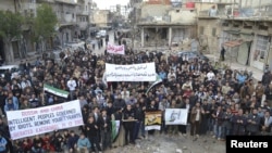 Demonstrators hold banners near damaged buildings during a protest against Syria's President Bashar al-Assad, after Friday prayers in Kafranbel near Idlib December 14, 2012. REUTERS/Raed Al-Fares/Shaam News Network/Handout (SYRIA - Tags: CIVIL UNREST MILI