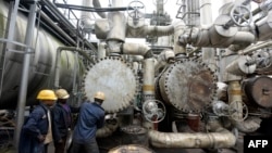 FILE - Workers try to tie a pipe at an oil refinery in Port Harcourt, Rivers State, Nigeria, Sept. 16, 2015.