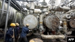 FILE - Workers try to tie a pipe at an oil refinery in Port Harcourt, Nigeria, Sept. 16, 2015. One of two state refineries in Port Harcourt will resume refining of crude oil in early August 2024, officials say.