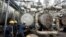 FILE - Workers try to tie a pipe at an oil refinery in Port Harcourt, Nigeria, Sept. 16, 2015. One of two state refineries in Port Harcourt will resume refining of crude oil in early August 2024, officials say.