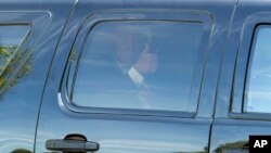 Donald Trump saluda desde su camioneta al salir de la reunión con los legisladores republicanos.