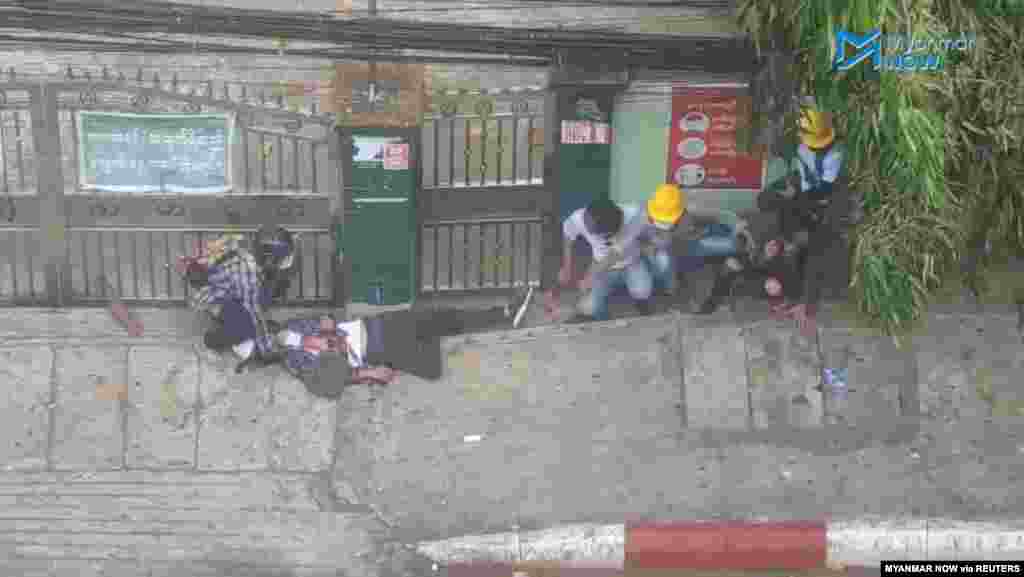 People approach an injured man with a gunshot wound amid protests against the military coup in Yangon, Myanmar, February 28, 2021, in this still image from video obtained via social media. (Credit: Myanmar Now)