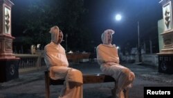 Volunteers play the role of 'pocong', or known as 'shroud ghost,' to make people stay at home amid the spread of coronavirus disease (COVID-19), outside the gate of Kepuh village in Sukoharjo regency, Central Java province, Indonesia, April 1, 2020.