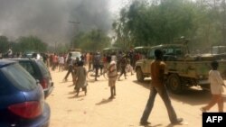 FILE - People look at smoke rising after suspected Boko Haram Islamists attack a military base in the northeast Nigerian city of Maiduguri. 