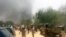 FILE - People look at smoke rising after suspected Boko Haram Islamists attack a military base in the northeast Nigerian city of Maiduguri. 