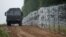 FILE - A view of a vehicle next to a fence built by Polish soldiers on the border between Poland and Belarus is seen near the village of Nomiki, Poland, Aug. 26, 2021.