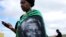 A woman, draped in a cloth with an image of former South African President Nelson Mandela, uses a mobile phone during Mandela's funeral at his ancestral village of Qunu in Eastern Cape province, south of Johannesburg, Dec. 15, 2013.