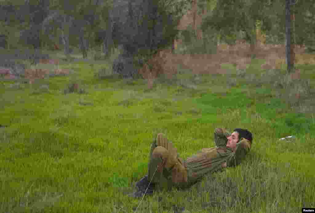 An Israeli reservist soldier waits at a field before heading home, near the border with the northern Gaza Strip November 22