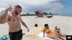 Cameron Baca, left, of Riverside County, California, puts on sunscreen while at Miami Beach, Florida's famed South Beach, Tuesday, July 7, 2020. Beaches in Miami-Dade County reopened Tuesday after being closed July 3-6 to prevent the spread of the…