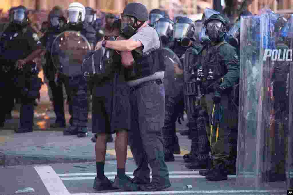 A police officer embraces a protester who helped disperse a crowd of people during a demonstration, June 1, 2020, in Atlanta, Georgia, over the death of George Floyd, who died after being restrained by Minneapolis police officers on May 25.
