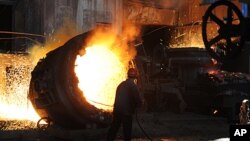 A worker stokes a giant burning cauldron at a steel mill in Hefei, in eastern China's Anhui province, June 25, 2011 (file photo)